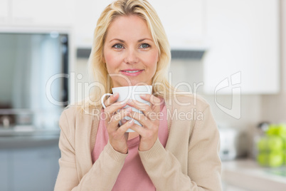 Beautiful young woman with coffee cup in kitchen