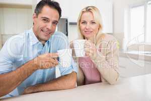 Portrait of happy couple with coffee cups in kitchen
