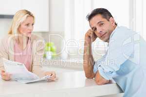 Upset couple with newspaper sitting in kitchen