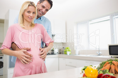 Portrait of a happy father with pregnant mother in kitchen