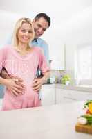 Portrait of a happy father with pregnant mother in kitchen