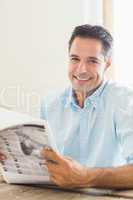 Smiling casual man with newspaper in kitchen