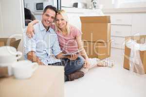 Couple using digital tablet amid boxes in new house