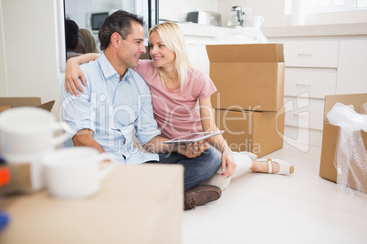 Couple using digital tablet amid boxes in a new house