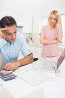 Worried couple with bills and laptop in kitchen