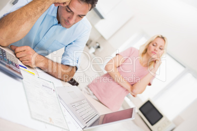 Worried couple with bills and laptop in kitchen