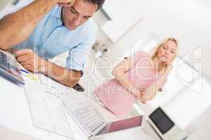 Worried couple with bills and laptop in kitchen