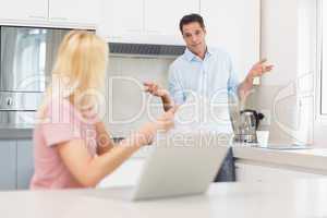 Couple with laptop and bill in the kitchen