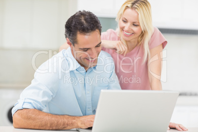 Happy couple using laptop in kitchen