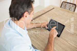 Concentrated man using digital table in kitchen