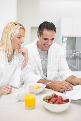 Couple having breakfast while reading newspaper in kitchen