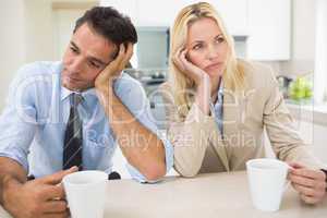 Well dressed thoughtful couple with coffee cups in kitchen