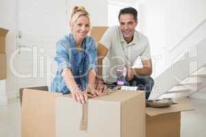 Smiling couple packing boxes in a new house