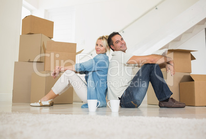 Smiling couple with cups and boxes in a new house