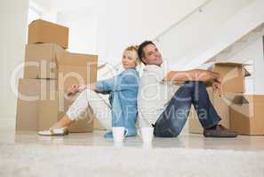 Smiling couple with cups and boxes in a new house