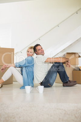Smiling couple with cups and boxes in a new house