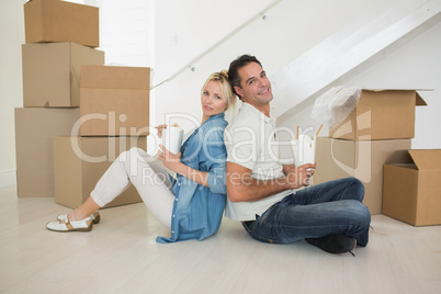 Smiling couple with takeaway food in a new house