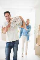 Couple carrying rolled rug after moving in a house