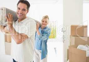 Couple carrying rolled rug after moving in a house