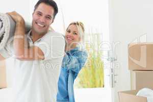 Couple carrying rolled rug after moving in a house