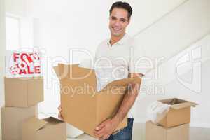 Smiling man carrying boxes in a new house