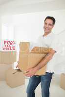 Cheerful man carrying boxes in a new house