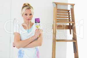 Beautiful woman holding paint brush in new house