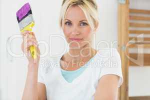 Beautiful woman holding paint brush in new house