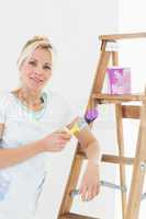 Beautiful woman holding paint brush in new house