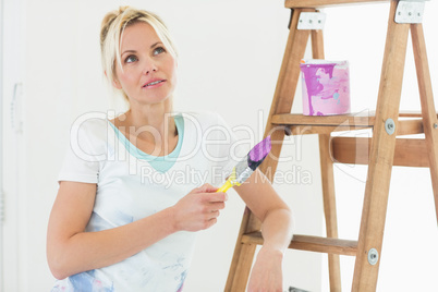 Beautiful woman with paint brush looking away in new house