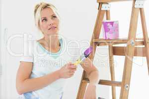 Beautiful woman with paint brush looking away in new house