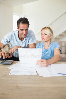 Concentrated couple with bills and calculator in living room