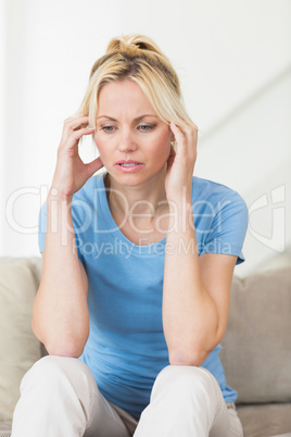 Worried young woman sitting in living room