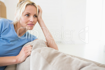 Thoughtful young woman sitting in living room