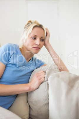 Worried young woman sitting in living room