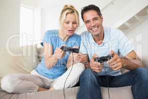 Cheerful couple playing video games in living room