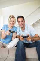 Cheerful couple playing video games in living room