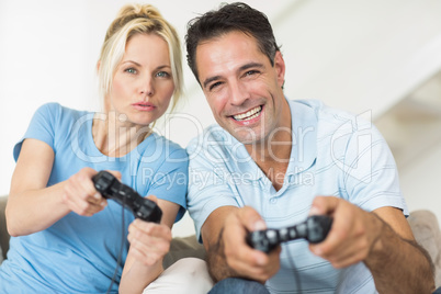 Cheerful couple playing video games in living room