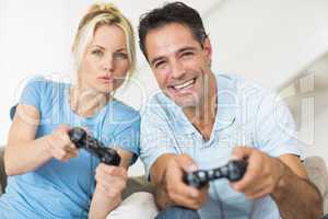 Cheerful couple playing video games in living room