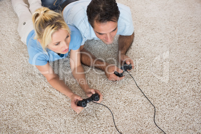 Couple playing video games on area rug at home