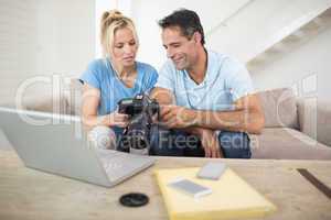 Couple with camera and laptop on sofa in living room