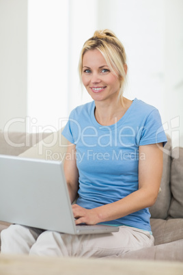 Portrait of a smiling woman using laptop in living room