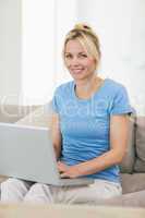 Portrait of a smiling woman using laptop in living room