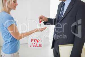 Real estate agent passing house key to woman