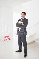 Smiling businessman with documents at an house for sale