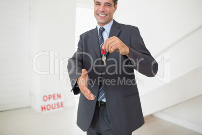 Businessman offering a handshake while holding up keys
