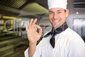 Smiling male cook gesturing okay sign in kitchen