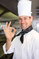 Smiling male cook gesturing okay sign in kitchen