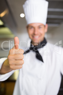 Smiling male cook gesturing thumbs up in kitchen