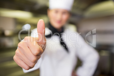 Blurred female cook gesturing thumbs up in kitchen